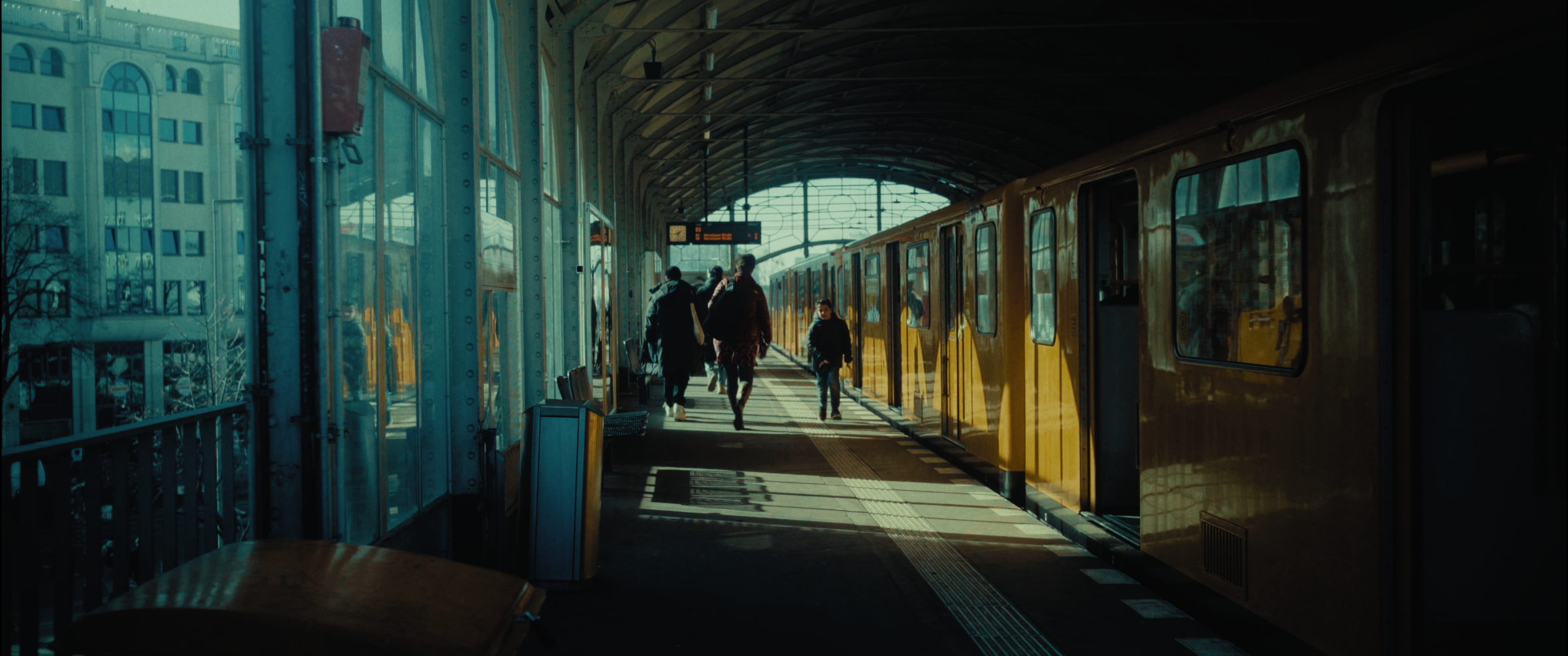 People walking along an elevated U-Bahn platform beside a train