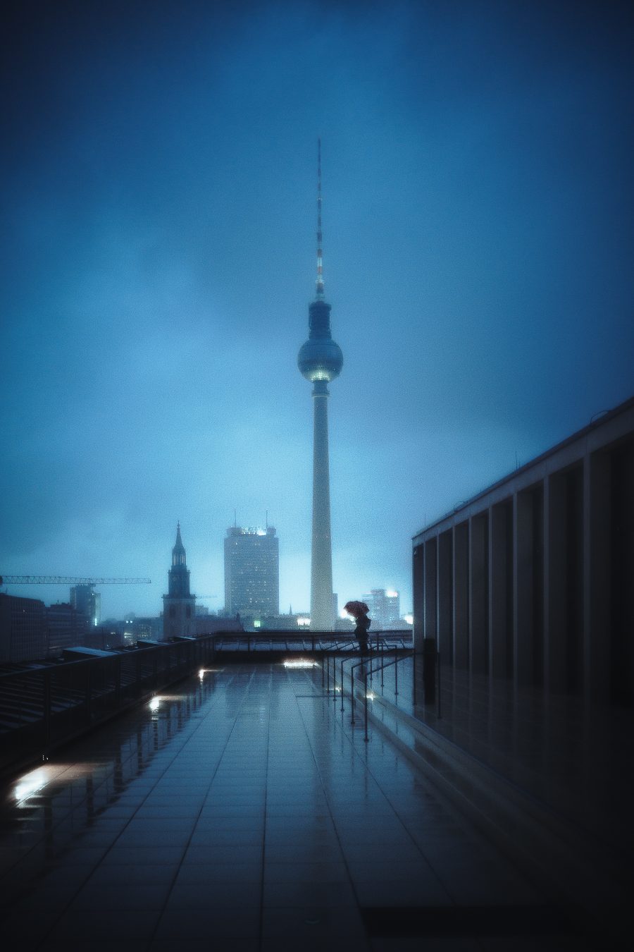 Fernsehturm television tower in rain and fog, one figure with an umbrella on a rooftop terrace